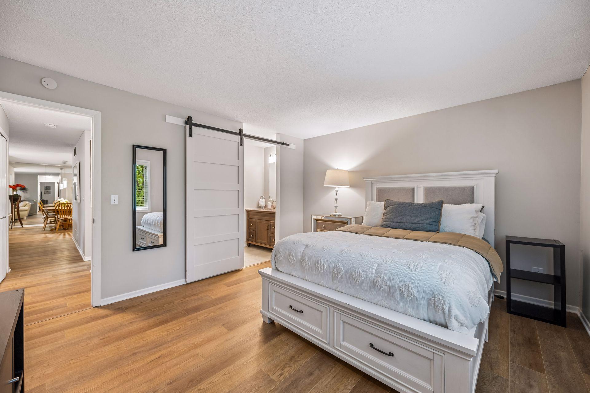 Primary features a spacious layout and a walk-in closet with a sliding barn-door creating privacy between the bedroom and updated bathroom