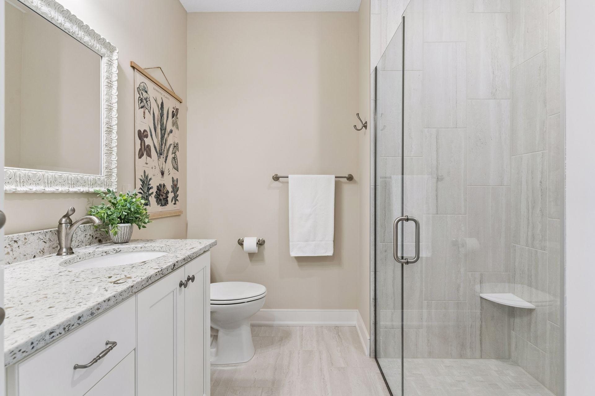 The private ensuite bath features a bright vanity area, tile shower, and quality finishes that make this main-floor bedroom ideal for guests or multi-generational living.