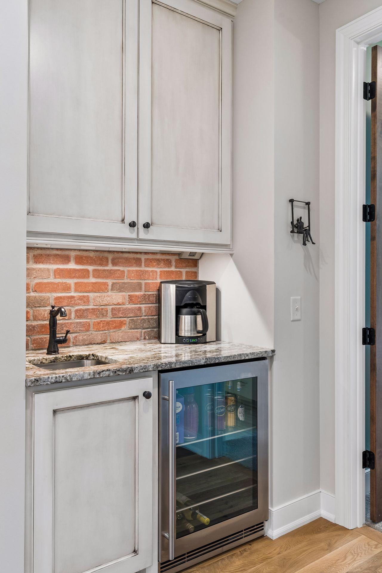 A dedicated coffee bar adds both function and luxury, complete with custom cabinetry, sink, water line, beverage center, and brick backsplash detail.