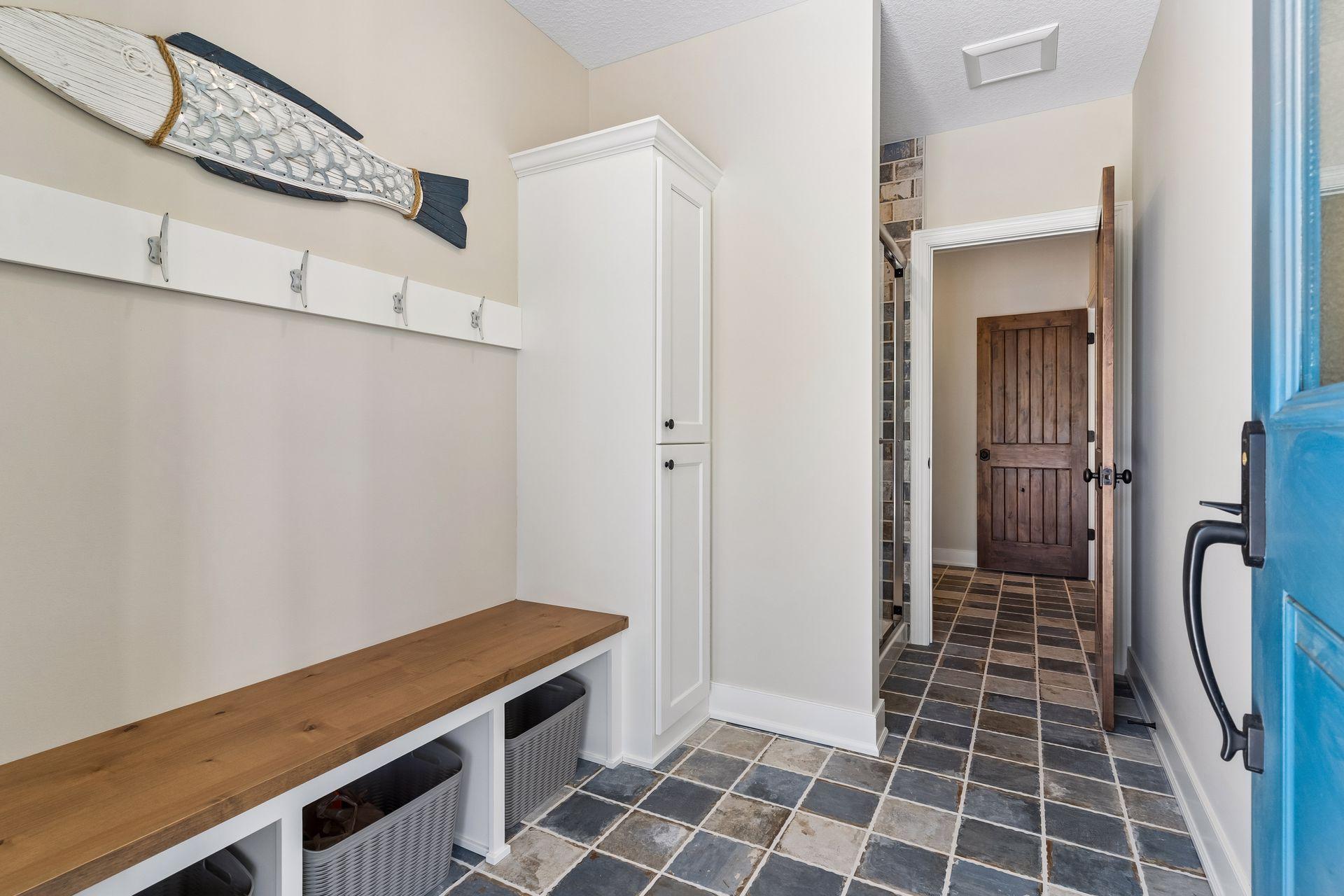 A functional pool-entry drop zone offers built-in bench seating, hooks, storage, and durable tile flooring—perfect for coming in from the pool or outdoor activities.