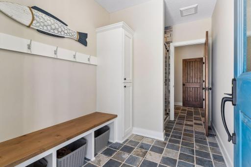A functional pool-entry drop zone offers built-in bench seating, hooks, storage, and durable tile flooring—perfect for coming in from the pool or outdoor activities.