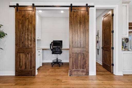 The built-in workstation features custom cabinetry and sliding barn doors, creating a polished and practical space for work, planning, homework, or household organization.