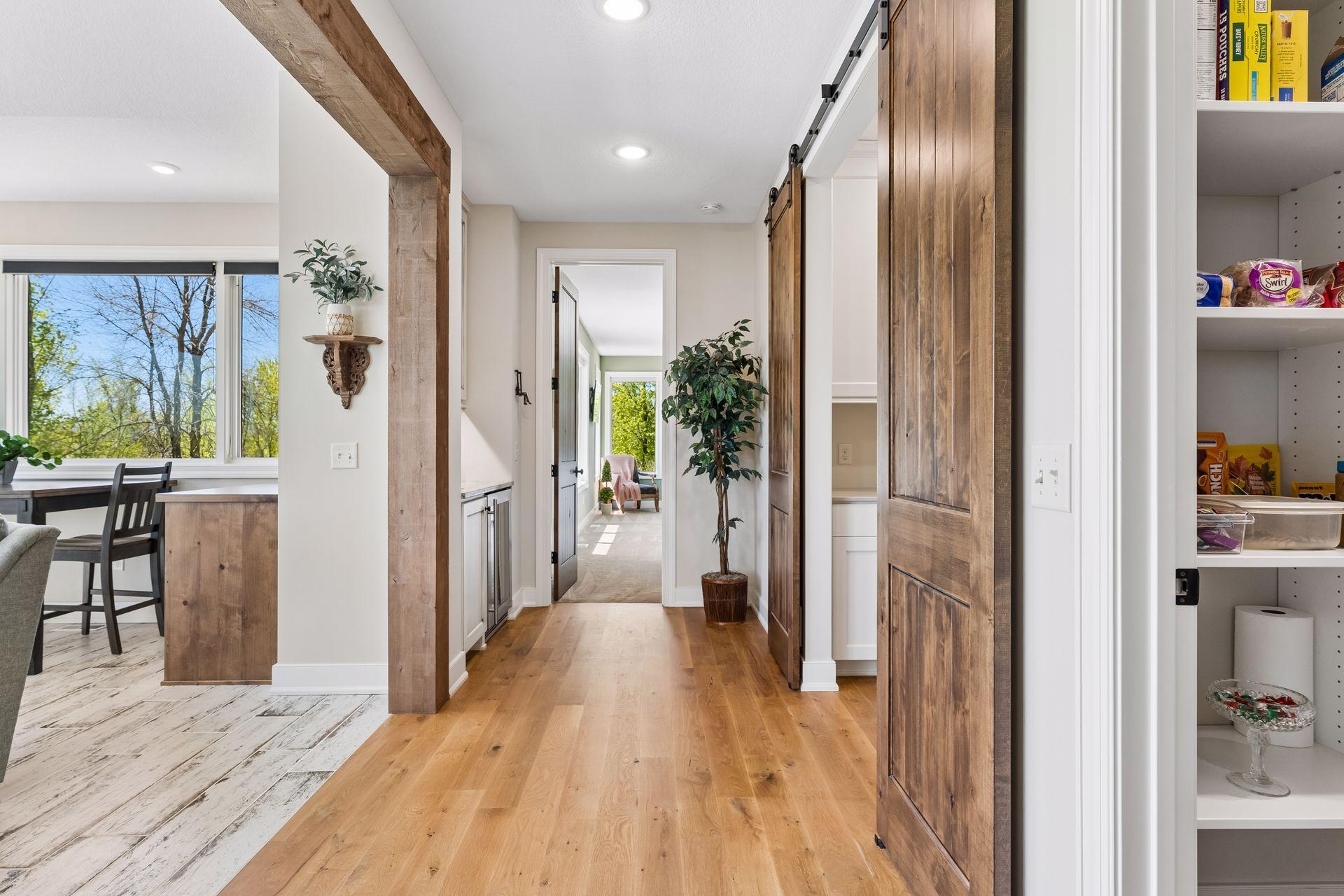 A thoughtfully designed hallway connects the main living spaces to everyday conveniences, including a large walk-in pantry, custom work station, coffee bar, and sunroom.
