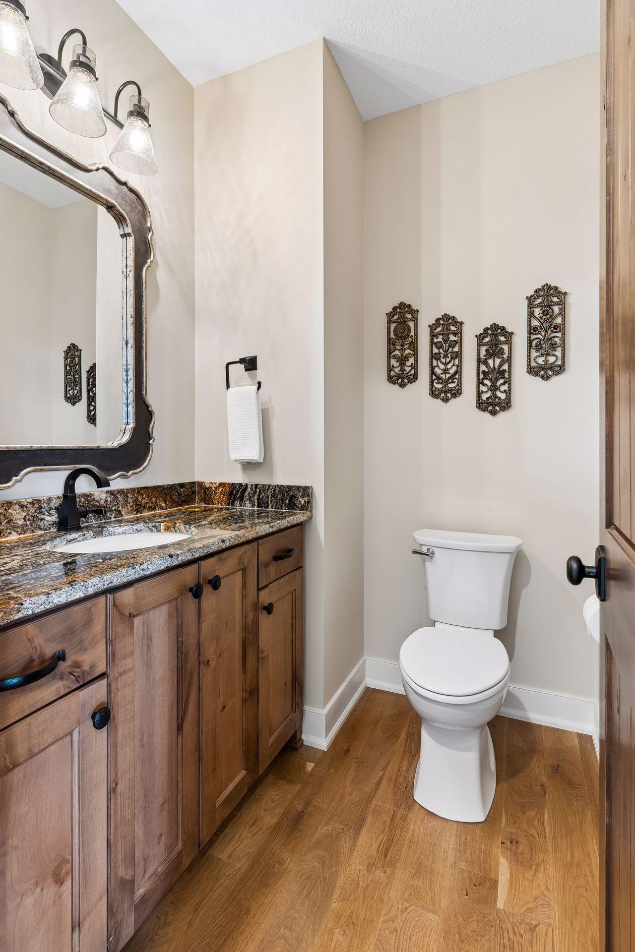A stylish main-floor powder room features warm wood cabinetry, stone countertop detail, and convenient placement for guests and everyday use.