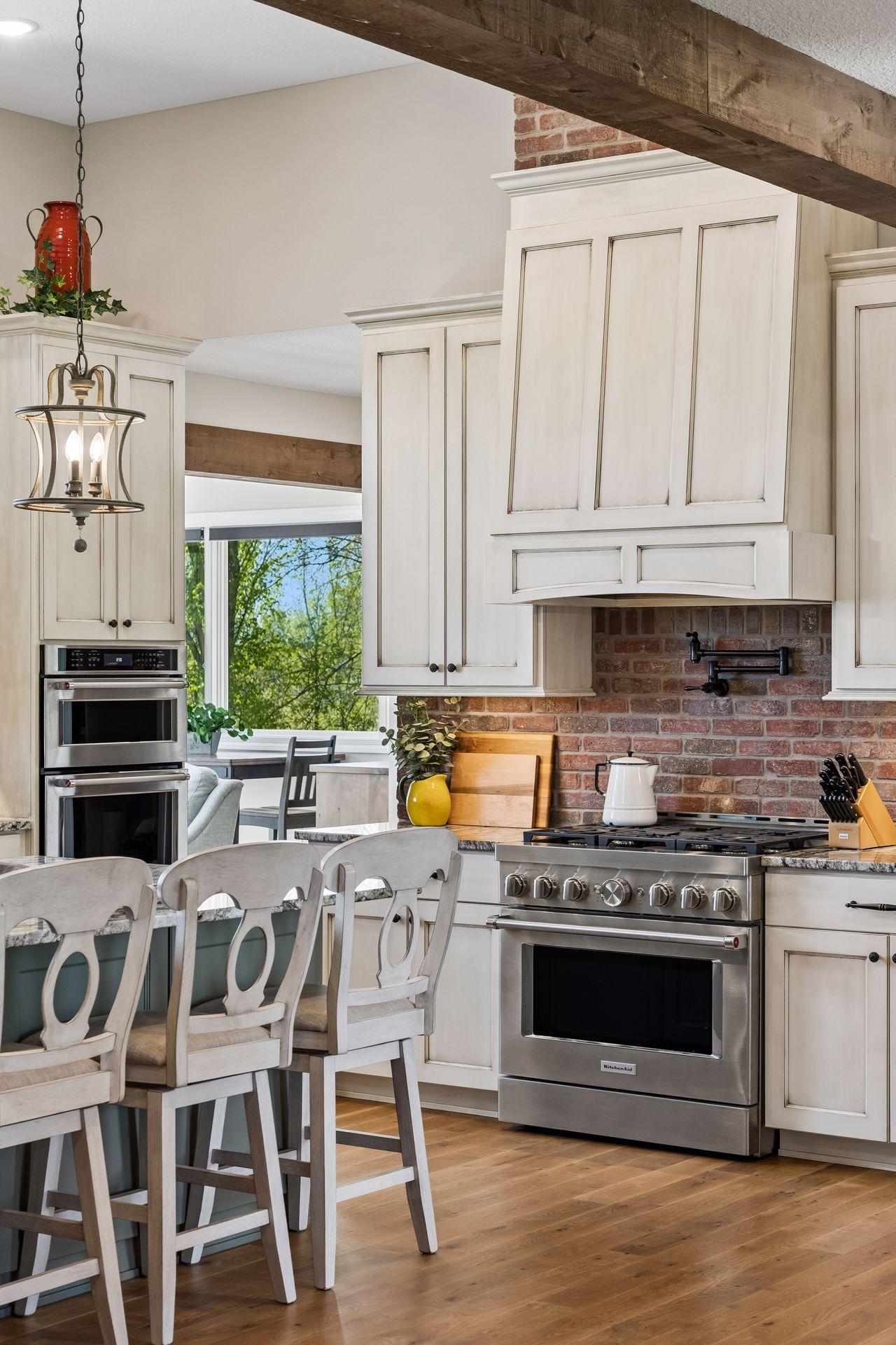 High-end kitchen finishes include custom cabinetry, a brick backsplash, stainless appliances, and thoughtful design details that bring warmth and function to the space.