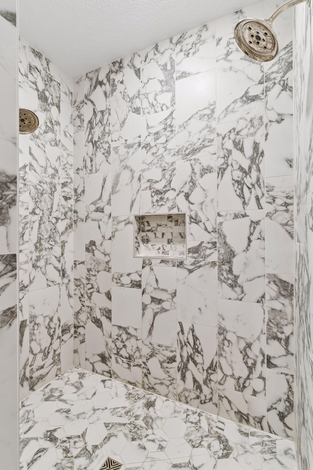 The fully tiled walk-in shower features dual shower heads and separate controls, completing the spa-like primary bath experience.