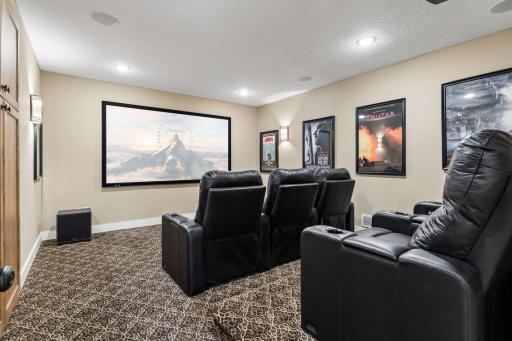 The dedicated theater room delivers a true at-home cinema experience with tiered seating, projector, large screen, and a private setting for movie nights.