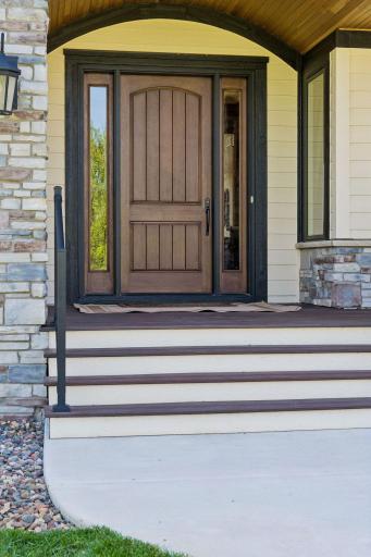 A welcoming covered entry featuring a natural cedar barrel ceiling, rich wood accents, stone details, and a statement front door that blends rustic elegance with luxury craftsmanship.