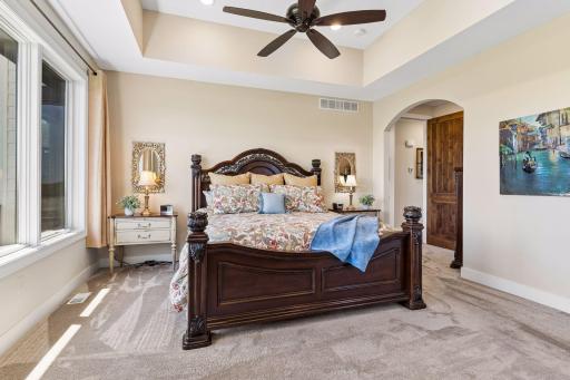 The south facing primary suite is filled with natural light and features large windows, a vaulted tray ceiling, ceiling fan, and a spacious layout designed for comfort and privacy.