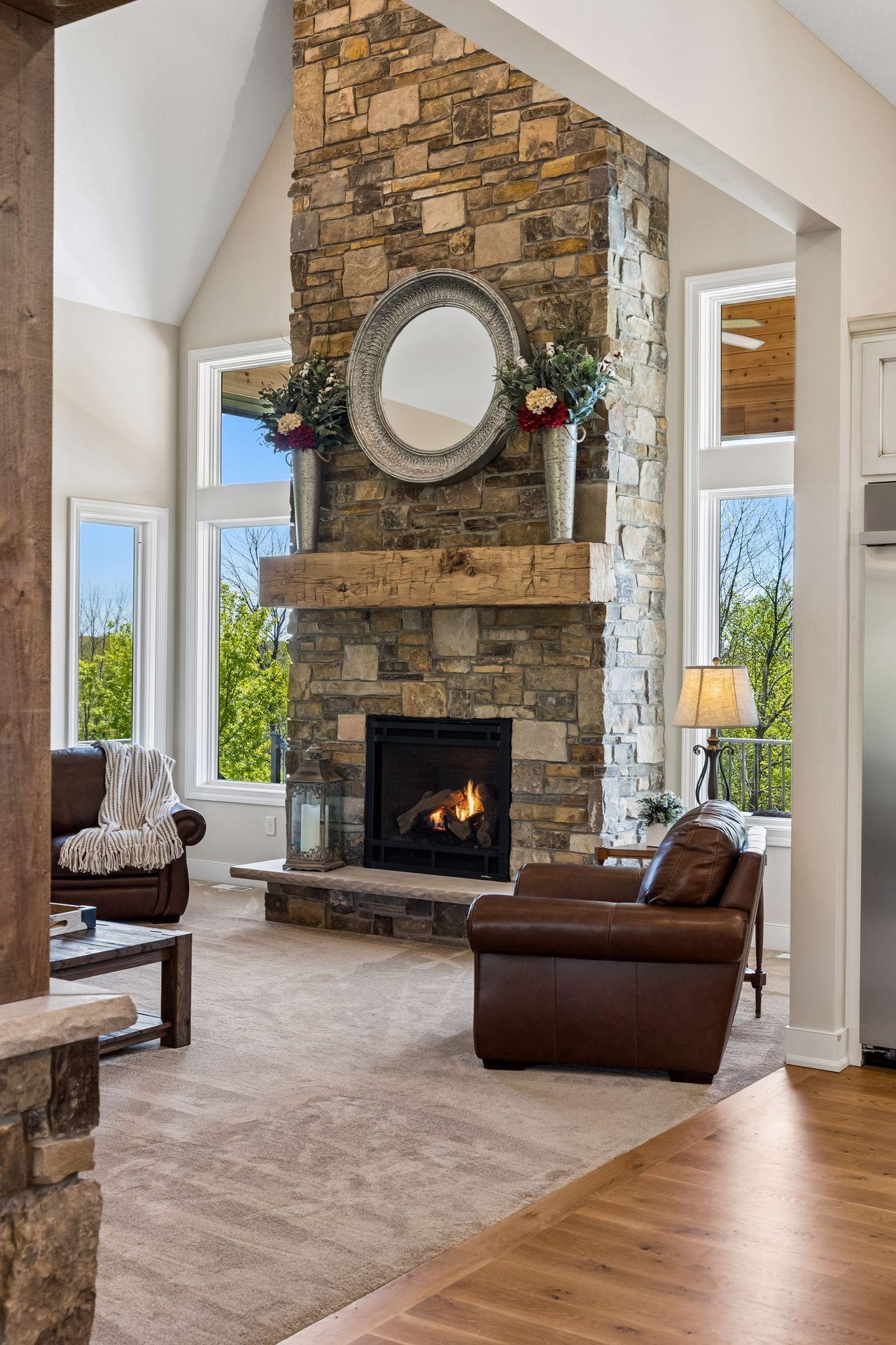 A closer look at the impressive stone fireplace, rustic wood mantel, and natural light that create a warm, inviting focal point in the heart of the home.