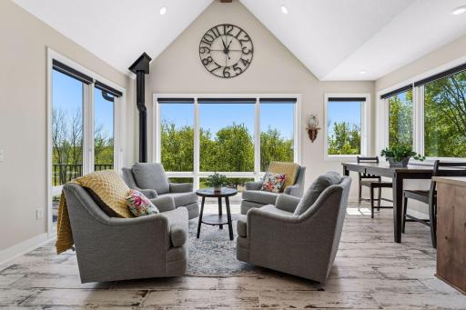 The four-season sunroom offers a bright and peaceful retreat overlooking the pool, complete with a gas stove fireplace, breakfast nook, walls of windows, and direct access to the deck for seamless indoor-outdoor living.
