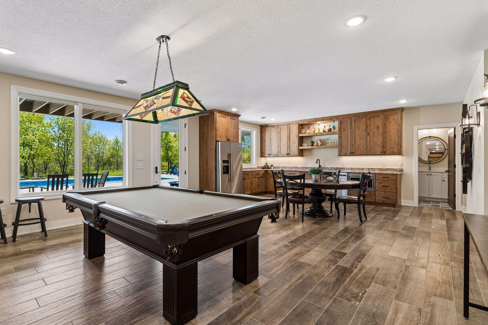 The walkout lower level is designed for entertaining, featuring a full kitchenette with custom alder cabinetry, expansive granite countertops, full-size appliances, and a game area with pool table.