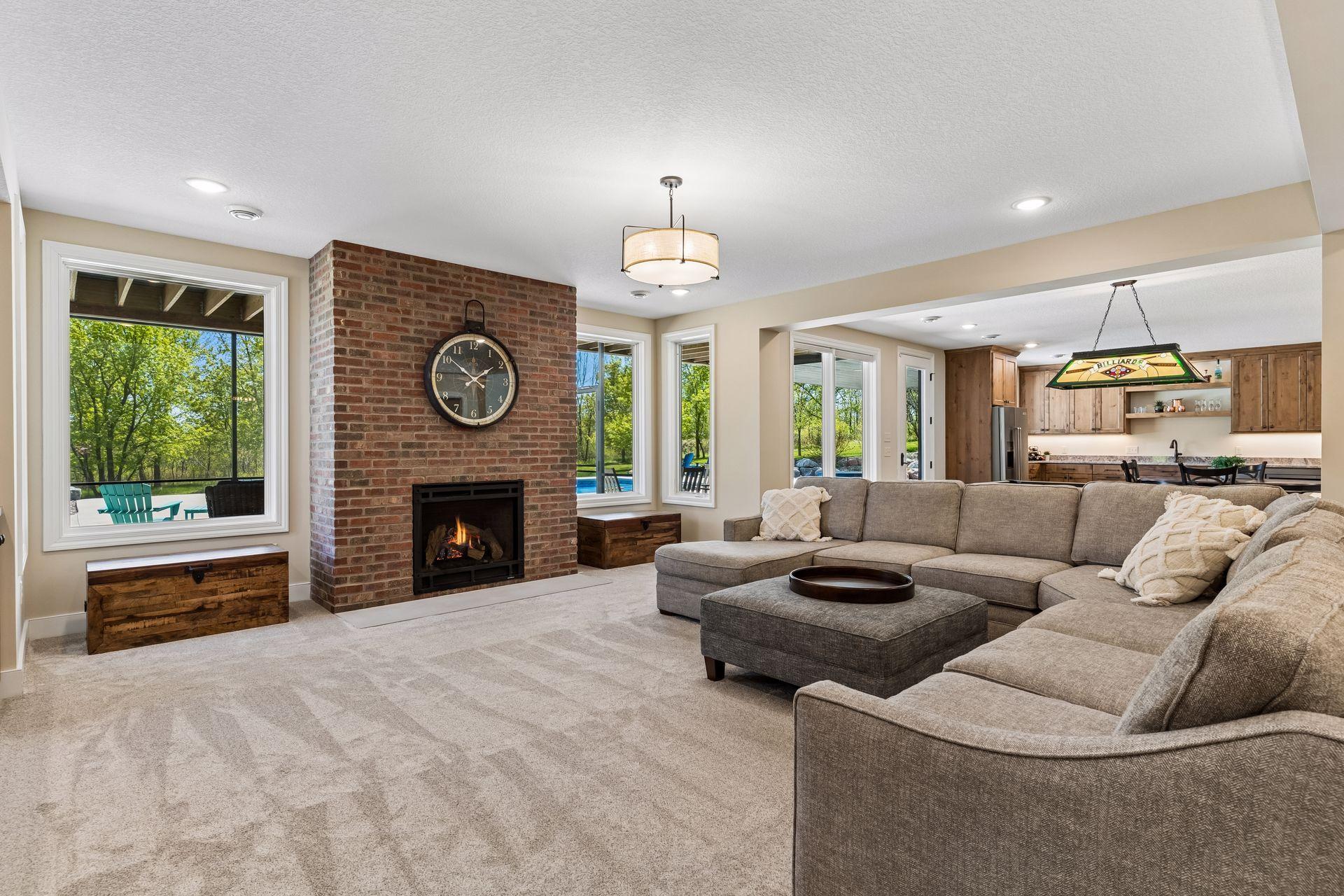 Large windows, a brick fireplace, and easy access to the pool area create a warm and inviting lower-level retreat for relaxing after a day outdoors.