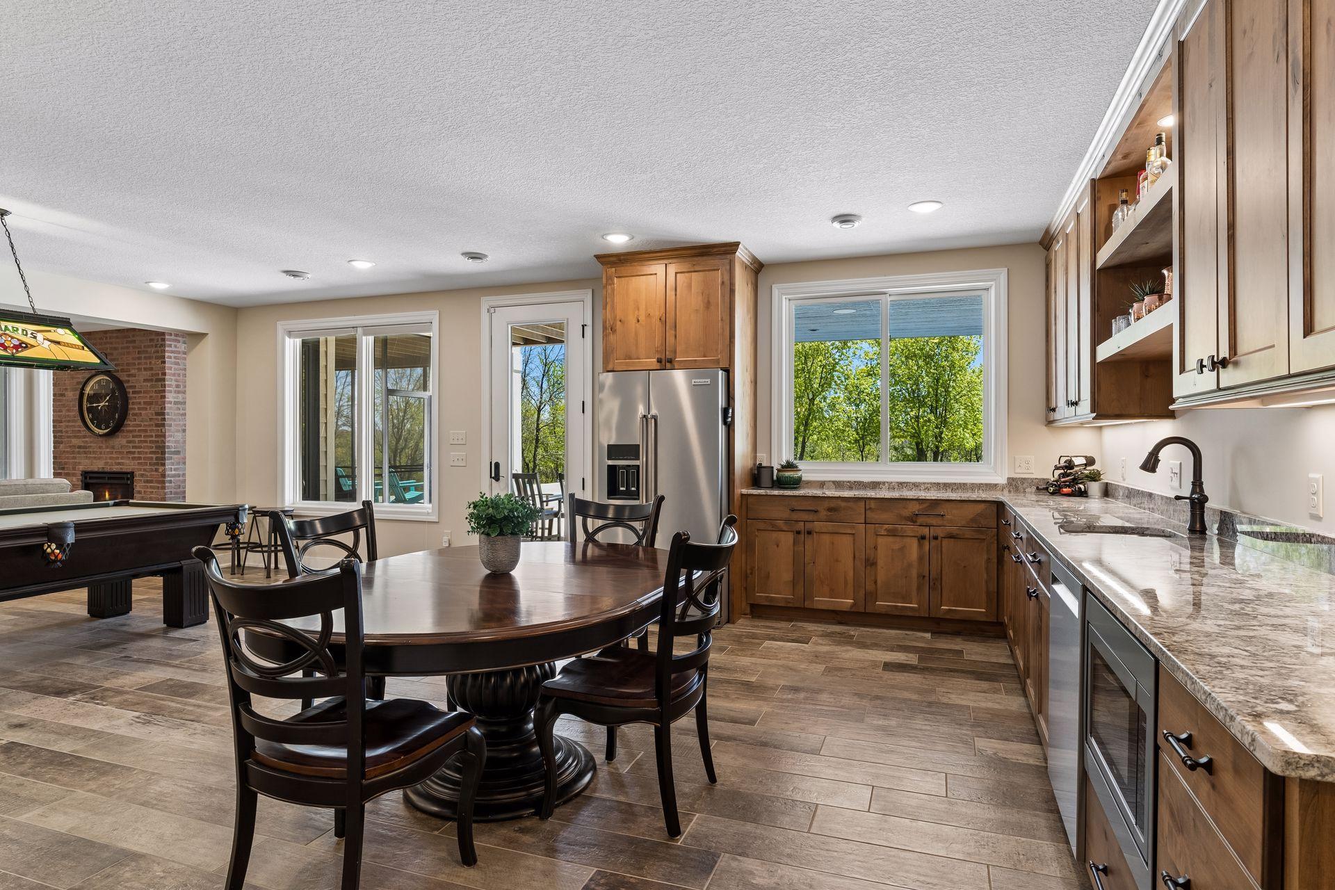 Custom alder cabinetry, open shelving, granite countertops, sink, and full-size appliances make the lower-level kitchenette ideal for hosting guests, pool days, or extended stays.