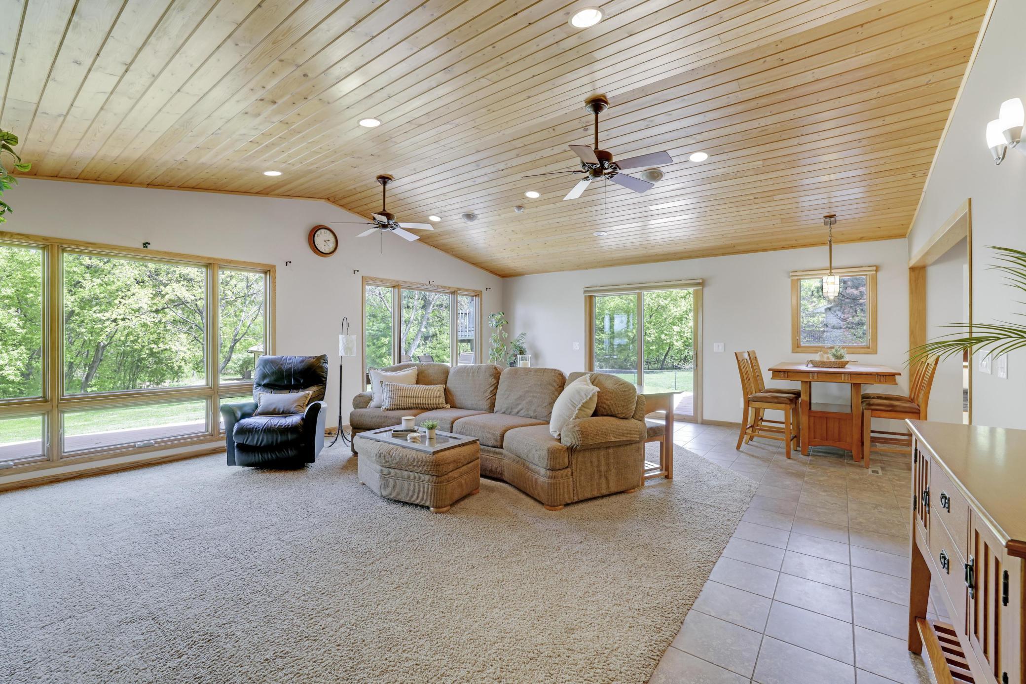 Large great room addition with wall of windows overlooking backyard and patio door onto deck.