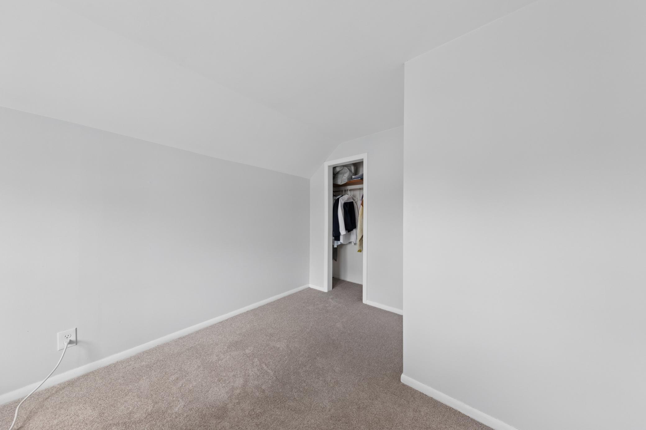 Spacious upper-level bedroom with cozy carpet, built-in storage, and closet access.