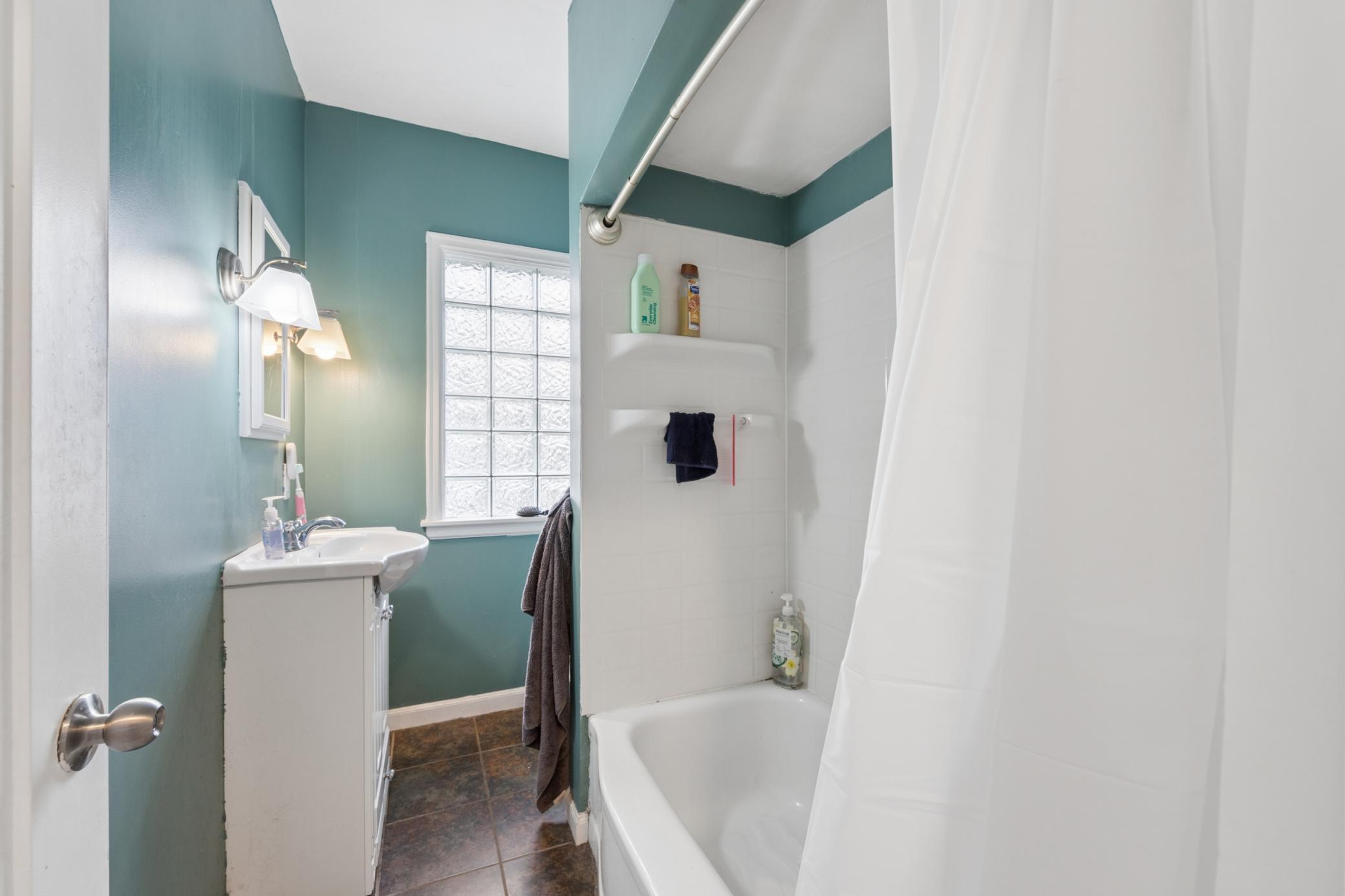 Clean and functional full bath featuring tiled shower/tub combo and updated vanity.