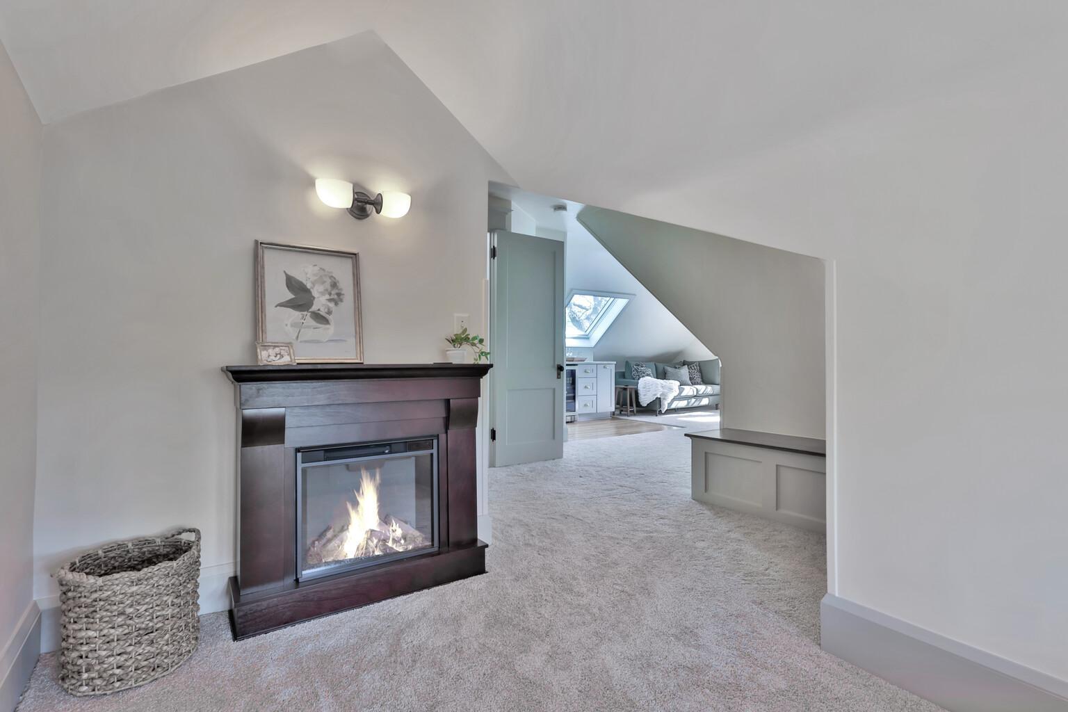 Discover your new favorite retreat! This cozy reading area features custom built-in shelving and a sun-drenched window seat, all tucked under charming sloped ceilings for a true sanctuary feel.