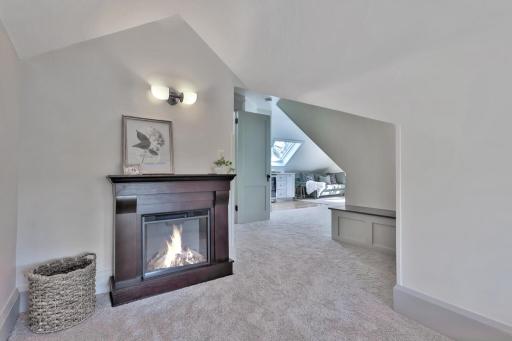 Discover your new favorite retreat! This cozy reading area features custom built-in shelving and a sun-drenched window seat, all tucked under charming sloped ceilings for a true sanctuary feel.