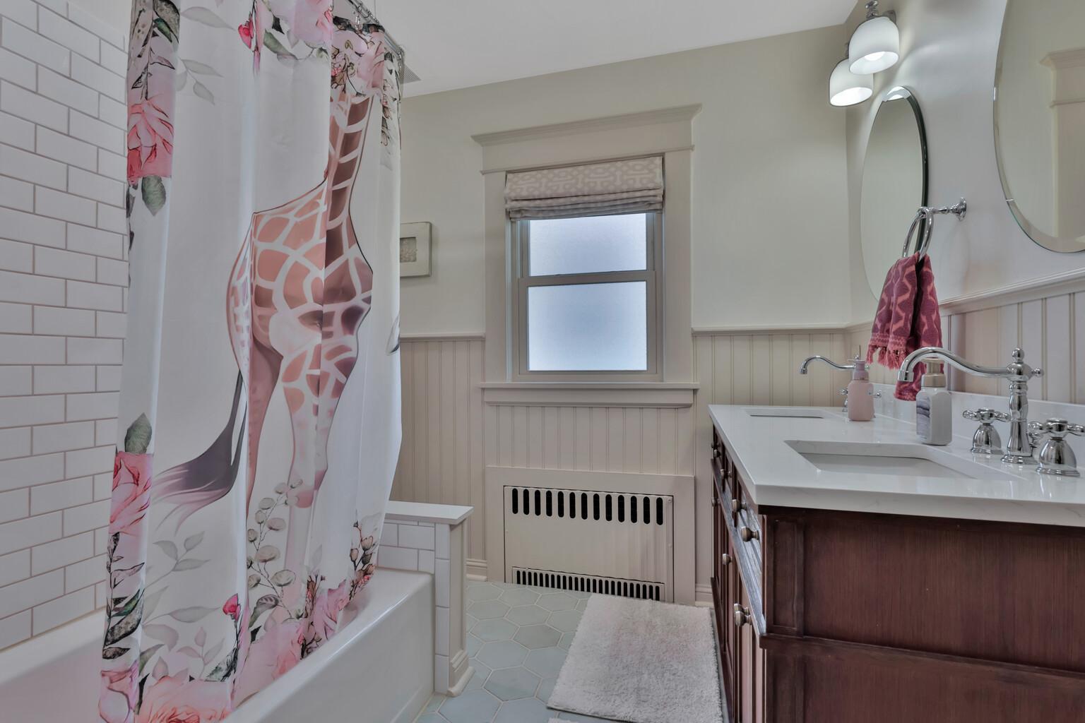 2nd-floor full bath, complete with radiant heated flooring and a dual-sink vanity. Beautifully finished with timeless beadboard detailing and crisp subway tilework.