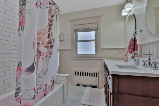2nd-floor full bath, complete with radiant heated flooring and a dual-sink vanity. Beautifully finished with timeless beadboard detailing and crisp subway tilework.