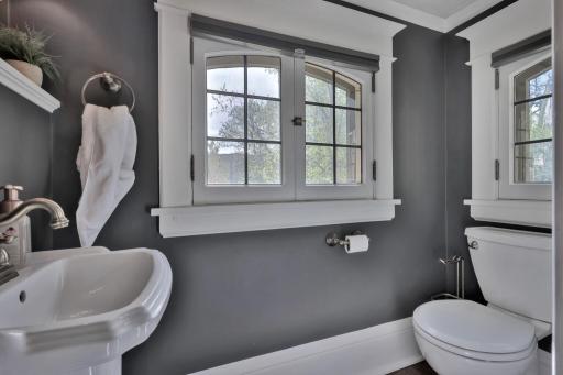 Newly added main-floor half bath featuring cozy heated floors and a classic pedestal sink. Designer charcoal walls, elegant sconce lighting, and timeless millwork create a chic, polished powder room for your guests.