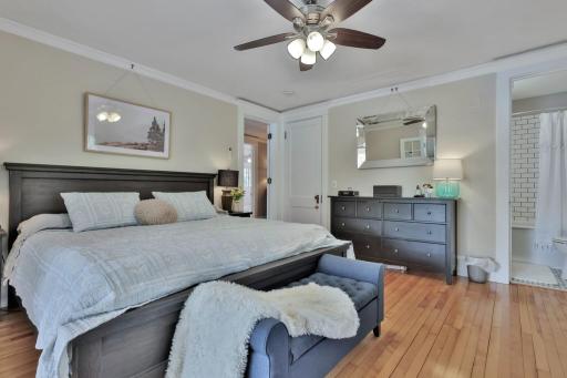 Spacious primary suite featuring polished hardwoods and elegant French doors that open to a sun-drenched sunroom. A private, peaceful retreat with natural wood ceilings and panoramic views.