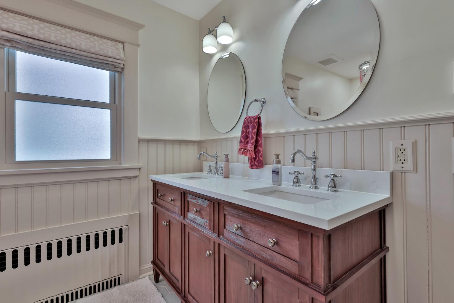 2nd-floor full bath, complete with radiant heated flooring and a dual-sink vanity. Beautifully finished with timeless beadboard detailing and crisp subway tilework.