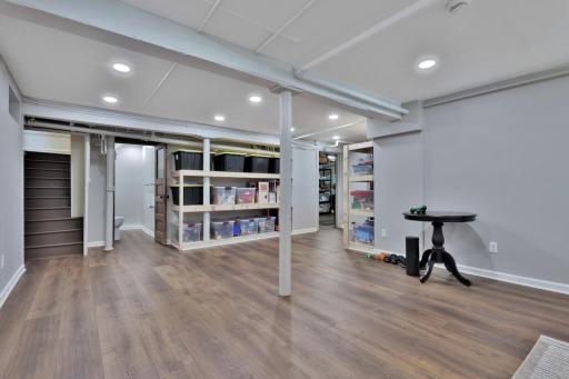 Bright, finished lower level featuring a spacious laundry suite. Boasts custom white cabinetry, ample counter space, and durable wood-look flooring. A clean, organized area with plenty of storage.