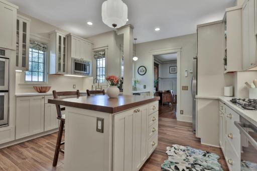 Stunning kitchen boasting leathered natural stone, professional enameled cabinets, & brass hardware. Includes a farmhouse sink, bar prep area with chiller, & tile backsplash over heated wood-look ceramic floors.