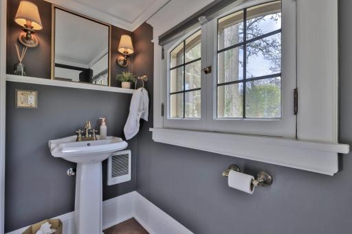 Newly added main-floor half bath featuring a classic pedestal sink, designer charcoal walls, elegant sconce lighting, and timeless millwork create a chic, polished powder room for your guests.