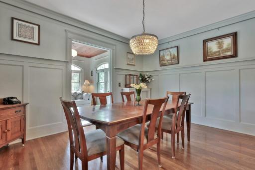 Grand dining room with a custom built-in buffet, classic plate rail, and gleaming hardwoods. Large windows and intricate woodwork create a stately setting.
