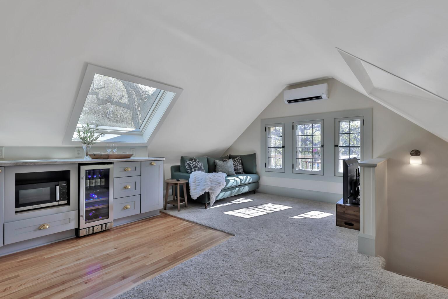 3rd floor retreat with custom wet bar, beverage chiller, microwave custom built-ins, bright with skylight, and window access to charming treetop deck.