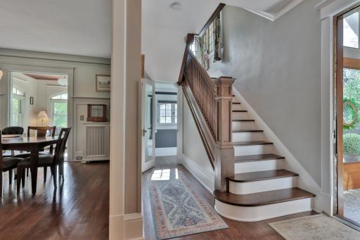 Grand staircase featuring beautiful natural wood millwork and a stately newel post. A breathtaking focal point.