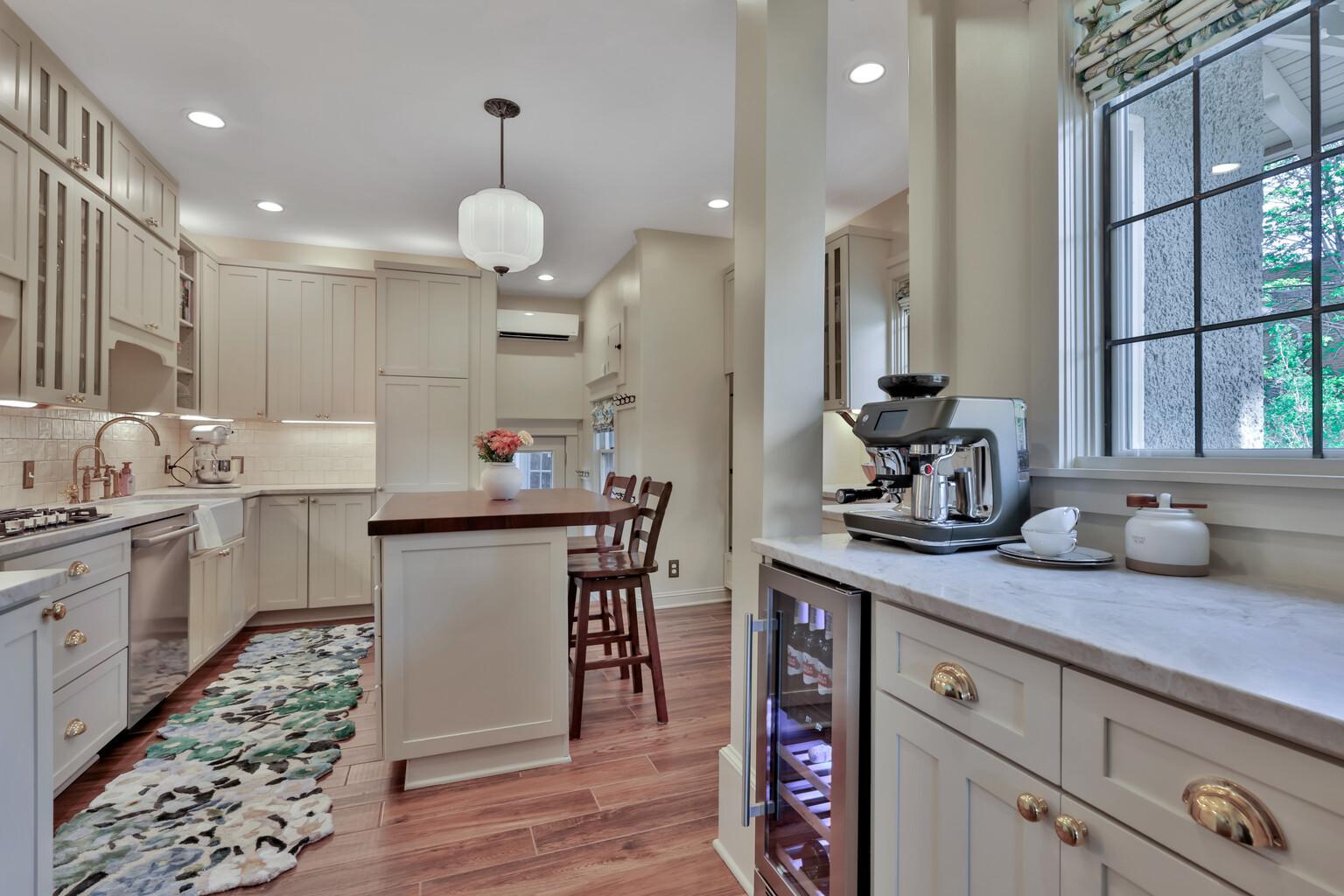 Stunning kitchen boasting leathered natural stone, professional enameled cabinets, & brass hardware. Includes a farmhouse sink, bar prep area with chiller, & tile backsplash over heated wood-look ceramic floors.