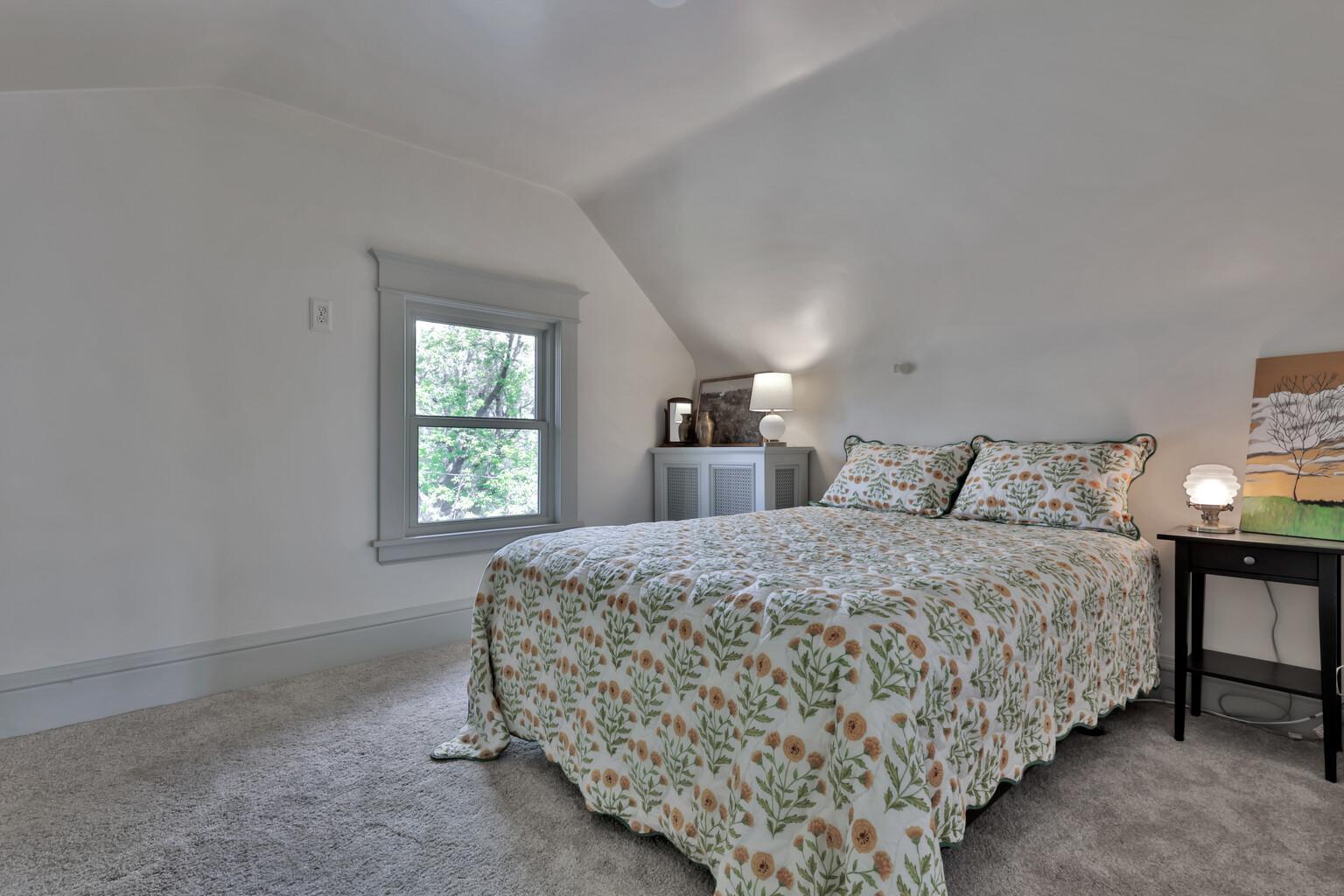 Tucked away on the top level, this peaceful 3rd-floor bedroom offers a private retreat. Featuring soft natural light, plush carpeting, and charming sloped ceilings for a cozy feel.