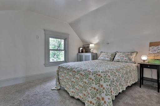 Tucked away on the top level, this peaceful 3rd-floor bedroom offers a private retreat. Featuring soft natural light, plush carpeting, and charming sloped ceilings for a cozy feel.