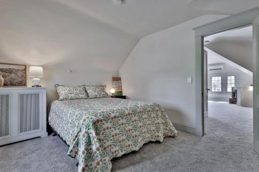 Tucked away on the top level, this peaceful 3rd-floor bedroom offers a private retreat. Featuring soft natural light, plush carpeting, and charming sloped ceilings for a cozy feel.