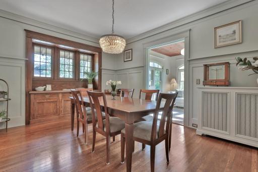 Grand dining room with a custom built-in buffet, classic plate rail, and gleaming hardwoods. Large windows and intricate woodwork create a stately setting.
