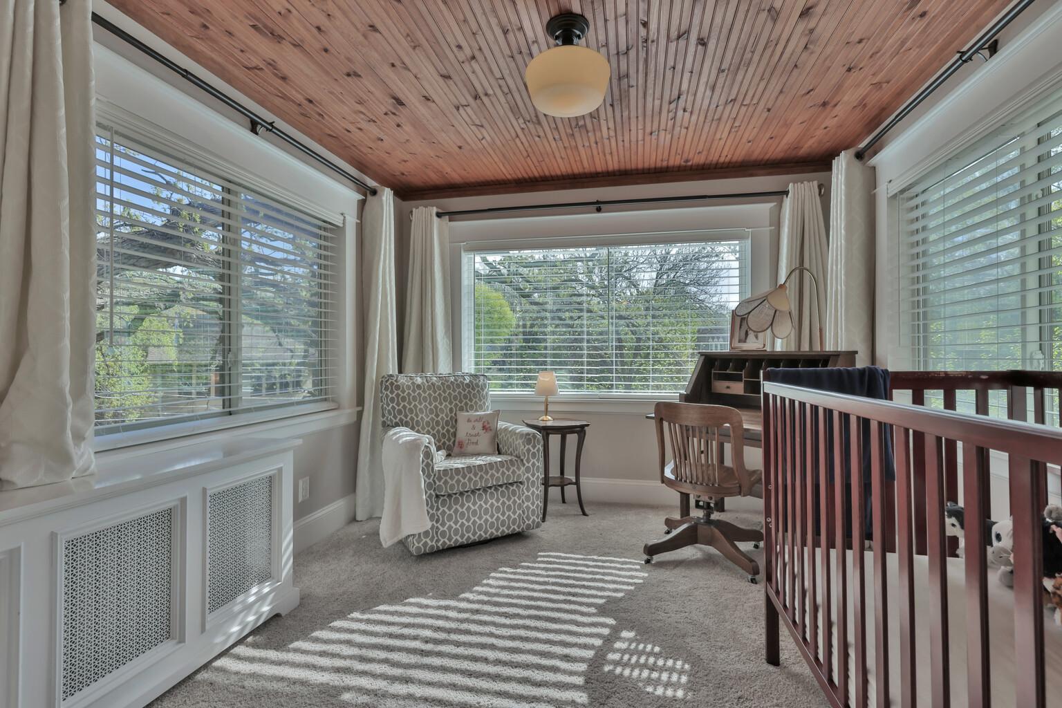 Connected to the primary suite, this bright sunroom boasts a stunning natural wood ceiling and classic radiator covers. Large windows offer serene views, creating a peaceful, airy retreat.