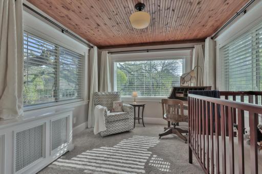 Connected to the primary suite, this bright sunroom boasts a stunning natural wood ceiling and classic radiator covers. Large windows offer serene views, creating a peaceful, airy retreat.