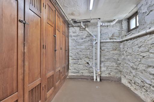 Step back in time with this original 1910 cold storage room. Boasting rugged limestone walls and historic wood cabinetry, this well-preserved space adds incredible soul and utility to the home.
