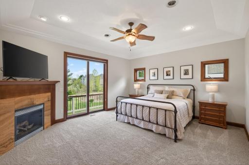 main level primary bedroom, tray ceilings, gas fireplace with stone and wood mantel surround.jpg