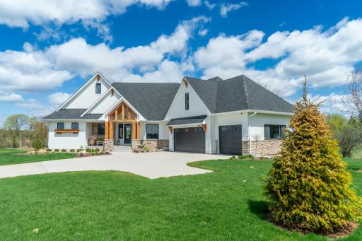 A stunning modern farmhouse with cedar timber accents, stone foundation, and a sweeping green lawn that makes every arrival feel like coming home.