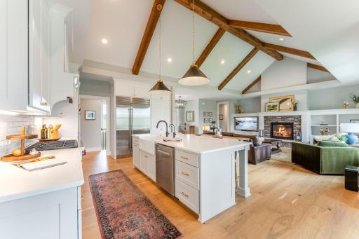 A chef's dream kitchen with white shaker cabinets, quartz countertops, a large island with gold hardware, and seamless flow into the living area. Designed for the way people actually live.