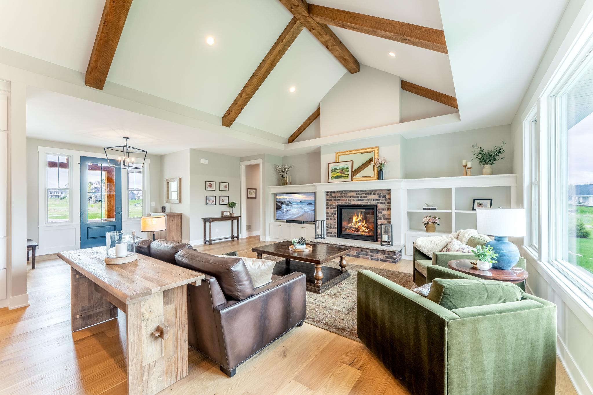 Soaring vaulted ceilings with hand-hewn wood beams, the warmth of the brick fireplace, and built-in shelving create the ultimate open-concept gathering space for family and entertaining.