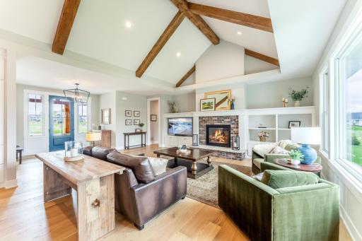 Soaring vaulted ceilings with hand-hewn wood beams, the warmth of the brick fireplace, and built-in shelving create the ultimate open-concept gathering space for family and entertaining.
