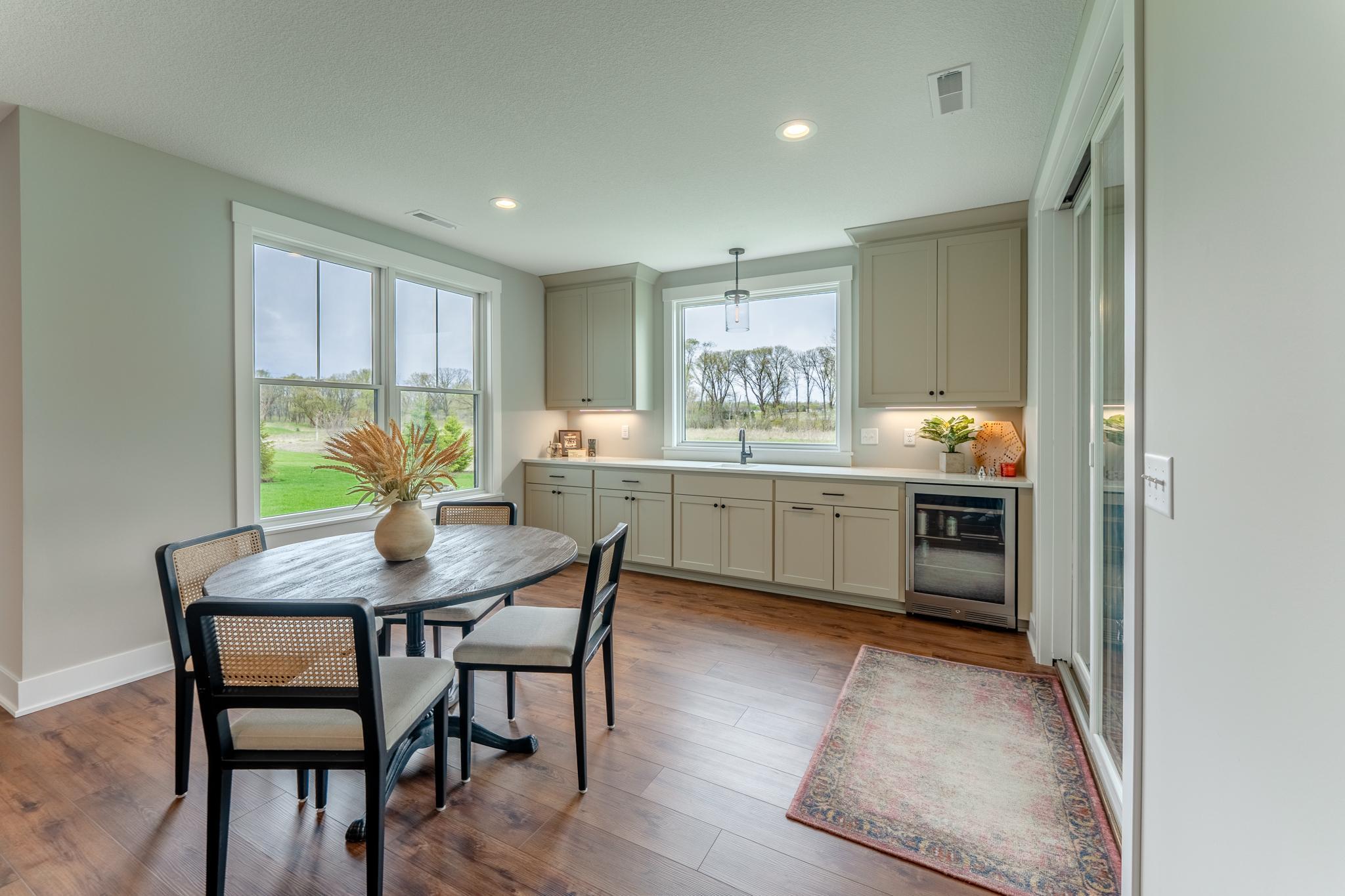 A stylish lower-level wet bar with built in cabinetry, a beverage fridge, and countryside views is an entertainer's dream that brings the party home.
