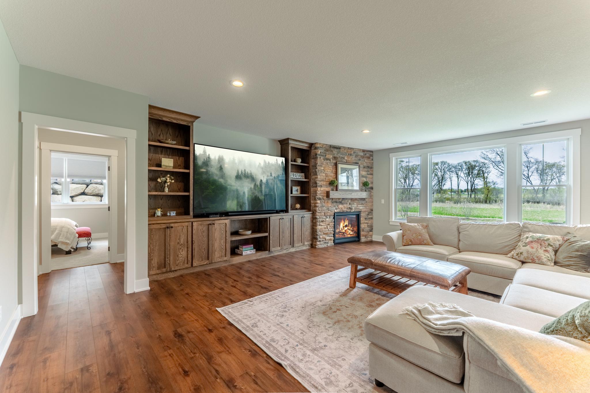 A spacious lower-level family room with a custom oak built-in entertainment wall, stone fireplace, and walkout access. It is the perfect space for movie nights, watching the big game or just relaxing with family or friends.