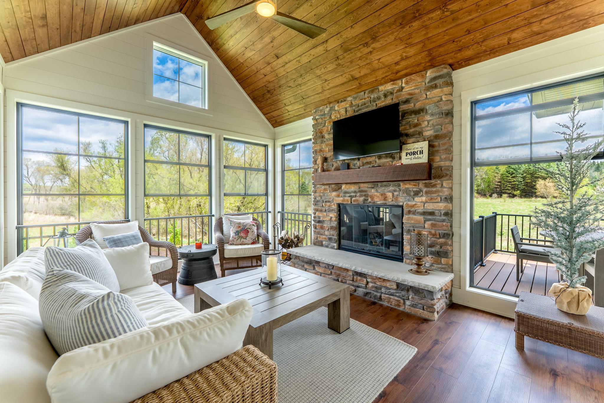 Step from the kitchen or dining area out to the screen porch with wood accents and stone woodburning fireplace.